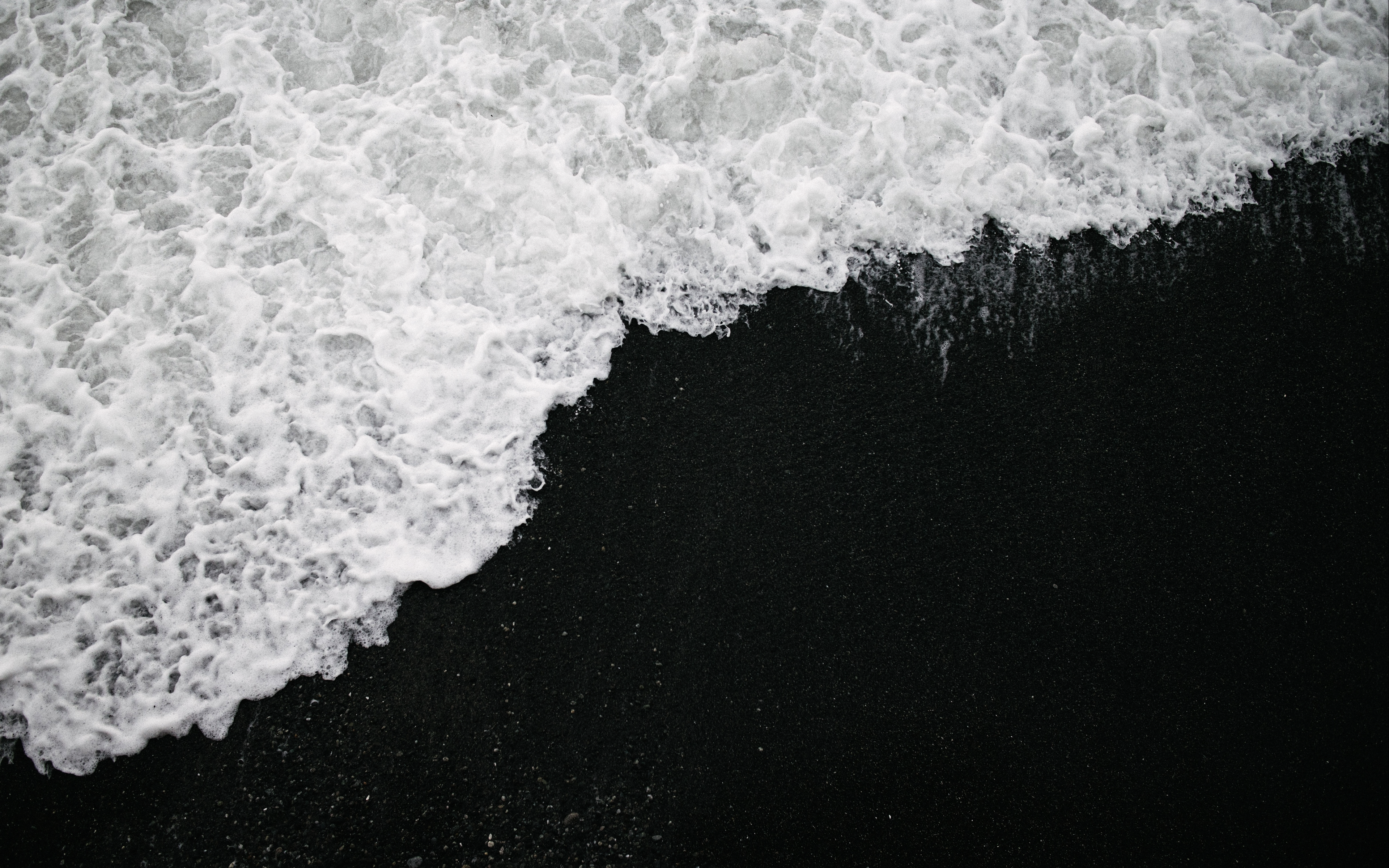 a_black_sand_with_white_foamy_waves.png